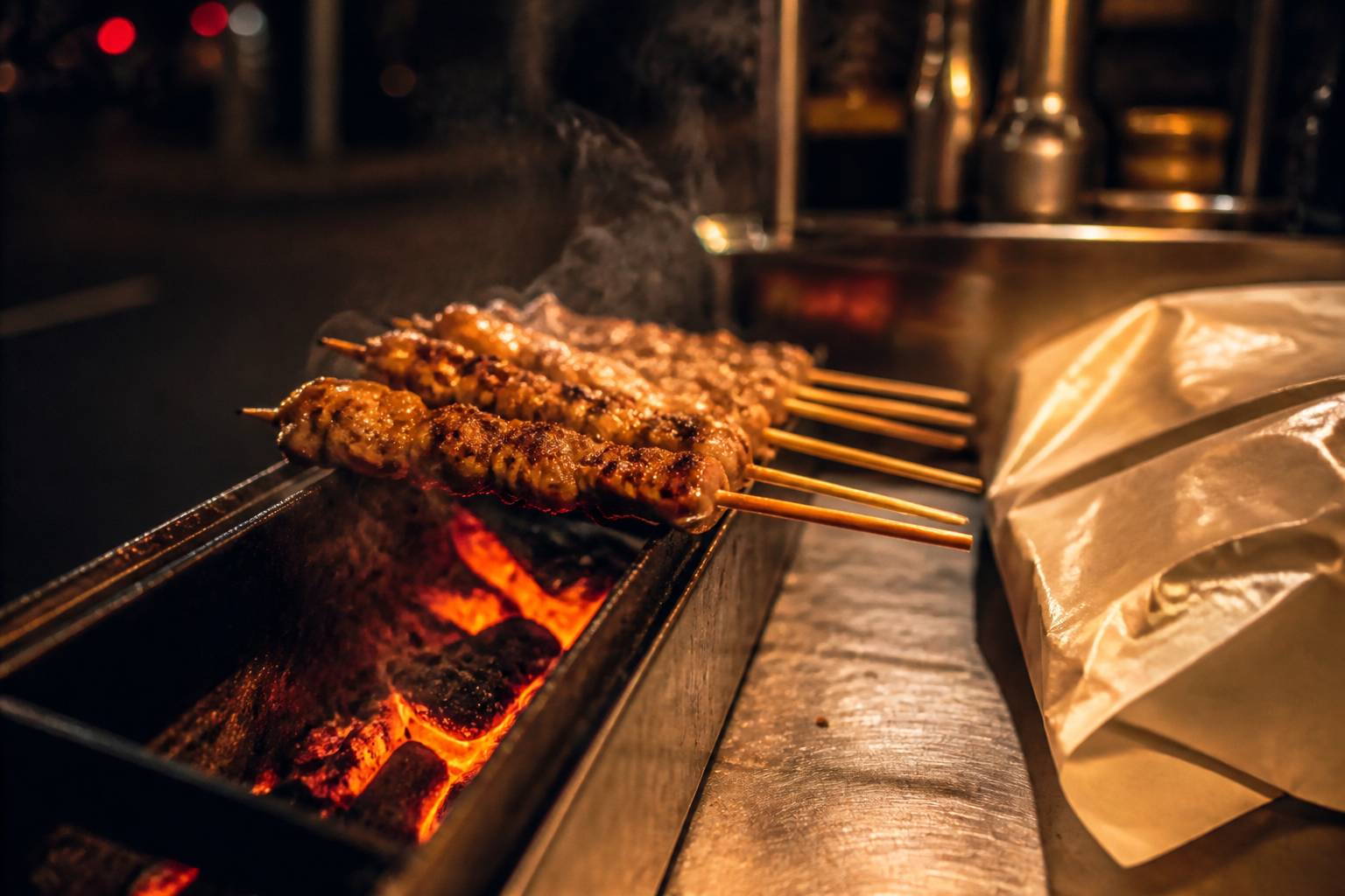 Brochettes grillant sur la braise orangée dans un comptoir de rue en inox