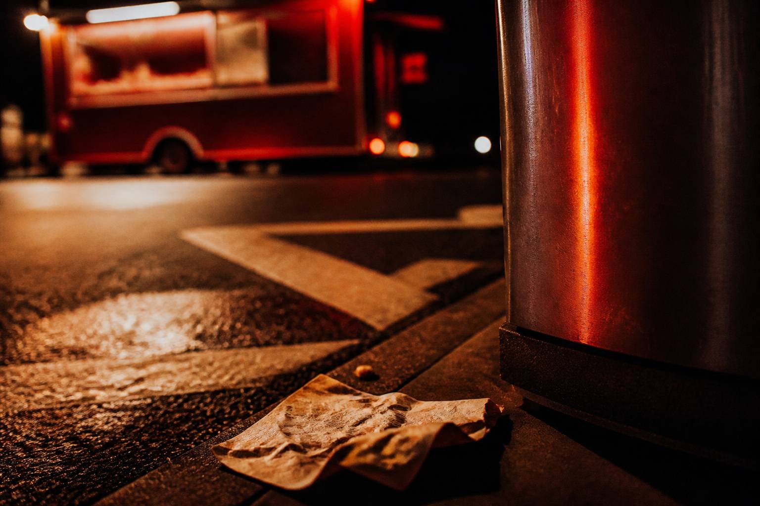 Coin de trottoir au marquage au sol avec un food truck flou en arrière-plan la nuit
