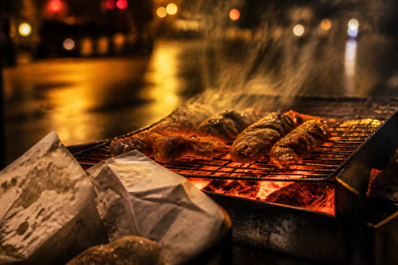 Grill de rue avec aliments en cuisson, fumée et braise orangée la nuit